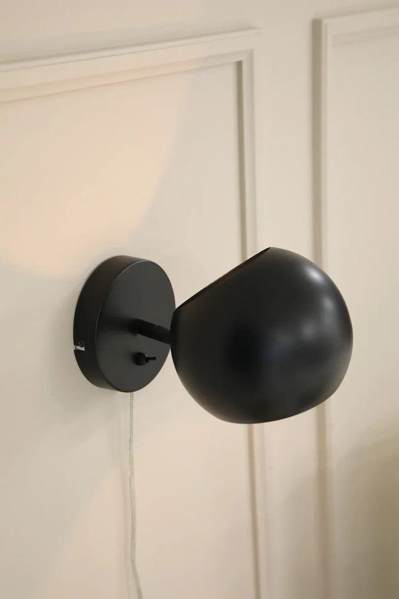 Zoomet helt ind på Edgar Væglampe i Sort hængt op på væggen i soveværelset