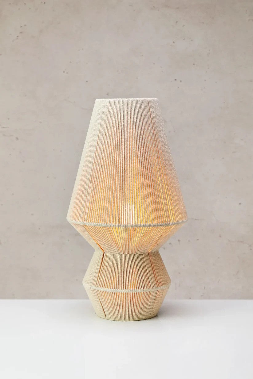 Den elegante Razzo Bordlampe 54cm i Beige sat på et bord foran en væg med en flot kontrast