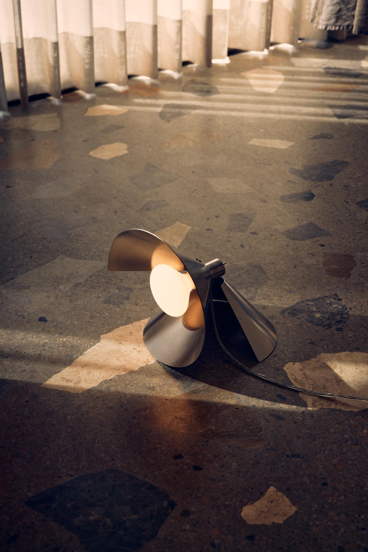 Frandsens Peel Table i Brushed Stainless Steel placeret på gulvet for den flotte kontrast