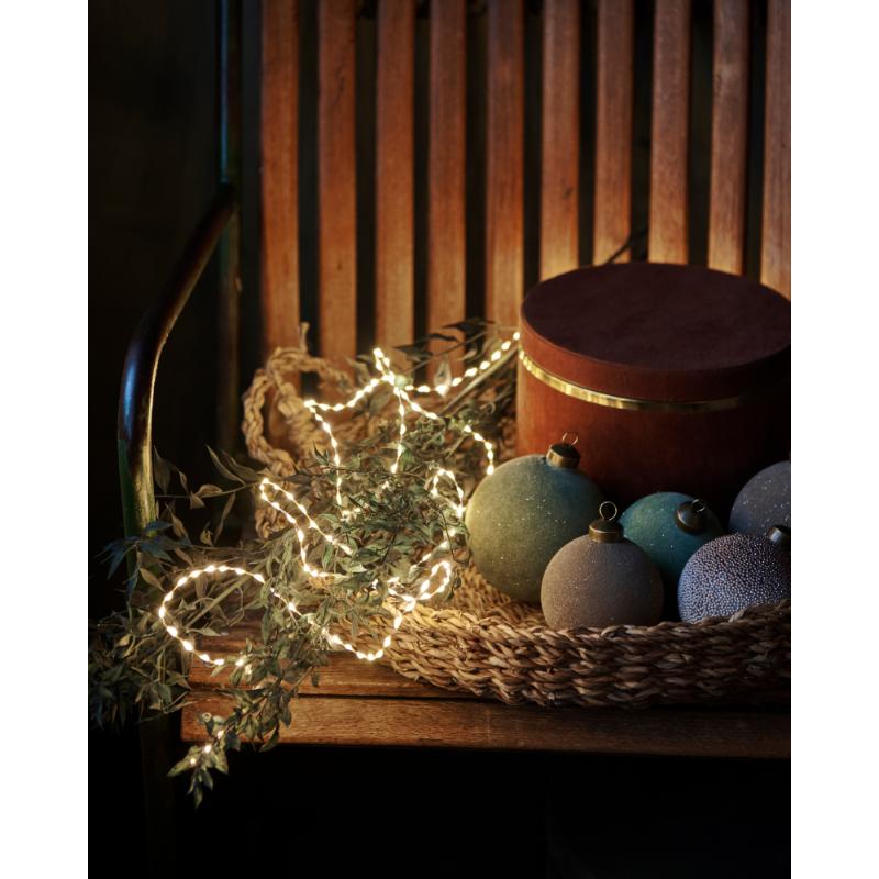 Den unikke Kiki 300 LED 4m i Guld placeret på en bænk for dens hyggelige belysning