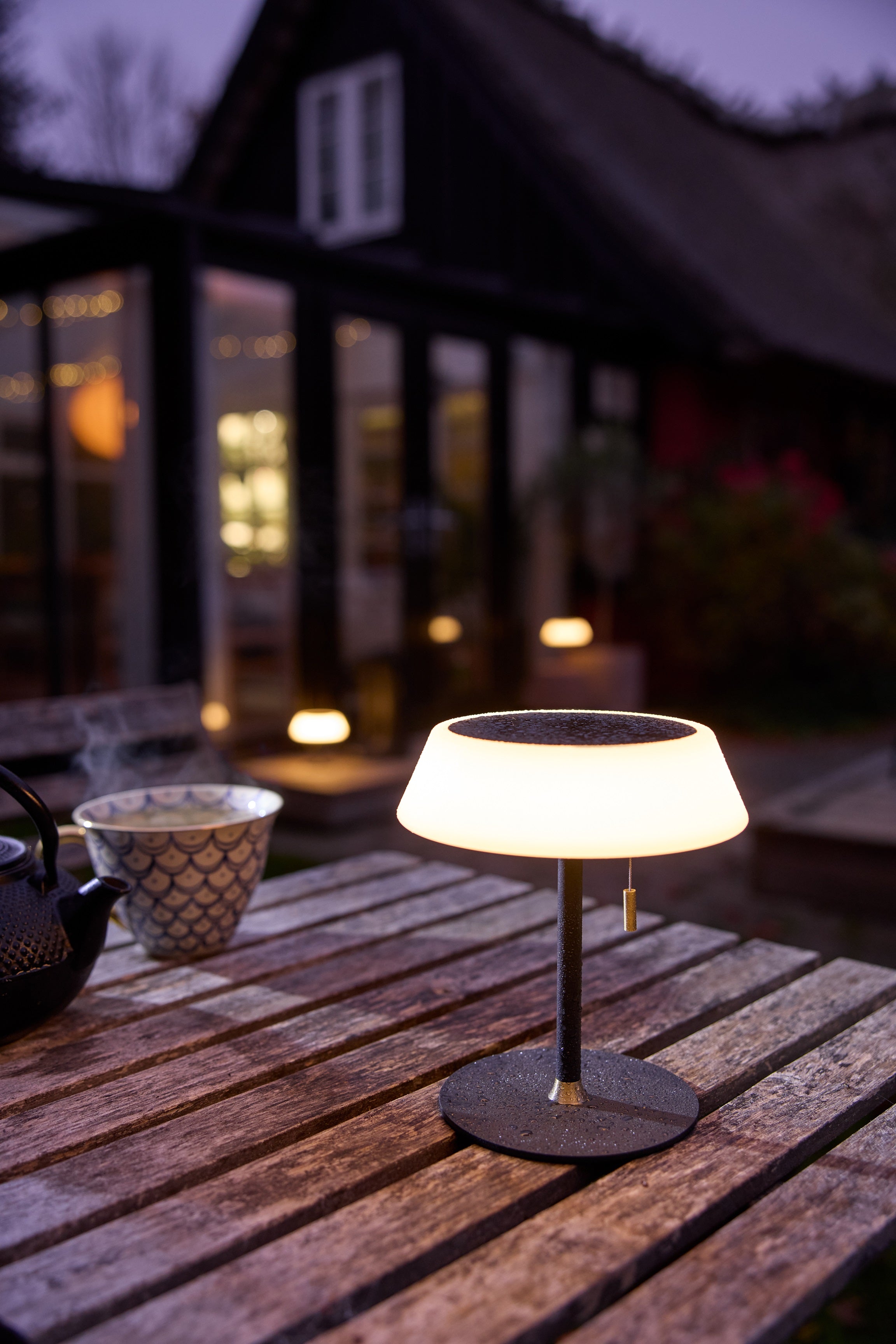 Den nye Solar Portable Table Lamp i Sort fra Halo Design udenfor på en bænk
