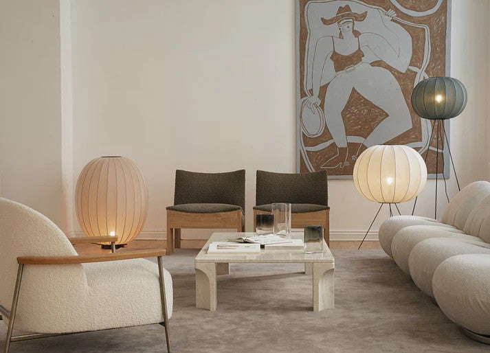 Den æstetiske Knit-Wit Ø60 Round Gulvlampe Medium i Pearl White placeret i stuen ved siden af sofaen for det æstetiske design og behagelige belysning