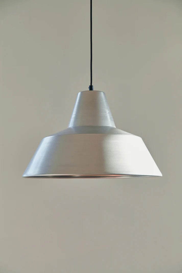 Den æstetiske Workshop Pendel W4 i Aluminium hængt op foran en væg for den flotte kontrast