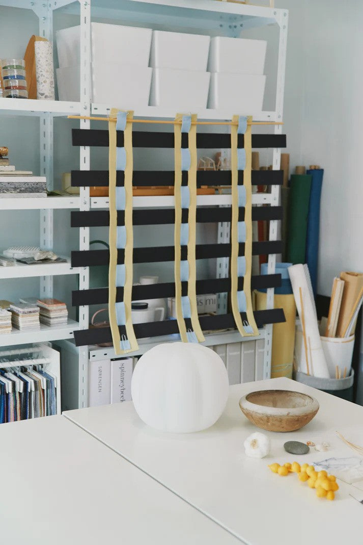 Den unikke designet Pepo Medium Ø30 Pendel i Hvid/Messing placeret på et bord