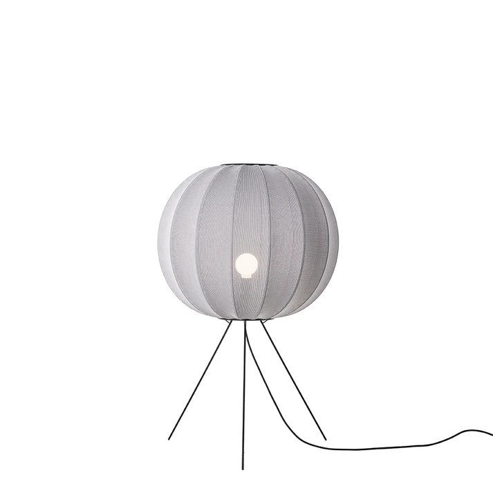 Den æstetiske Knit-Wit Ø60 Round Gulvlampe Medium i Silver placeret foran en hvid væg for en flot kontrast med en E27 pære iført