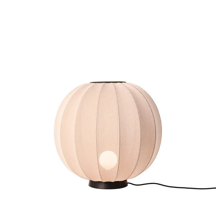 Den elegante Knit-Wit Ø60 Round Gulvlampe Level i Sand Stone placeret på gulvet foran en hvid væg med en E27 pære iført og tændt