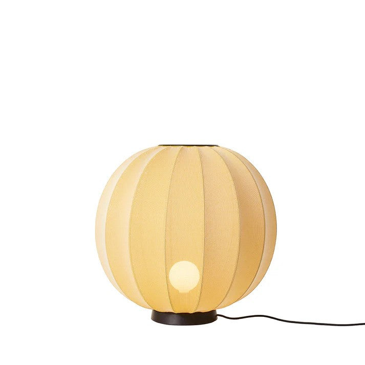 Den æstetiske Knit-Wit Ø60 Round Gulvlampe Level i Sunrise placeret på gulvet med en E27 pære iført og tændt