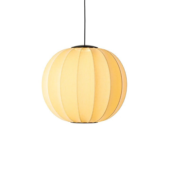 Den æstetiske Knit-Wit Ø60 Round Pendel LED i Sunrise hængt op foran en væg og tændt for sin indbygget LED Module