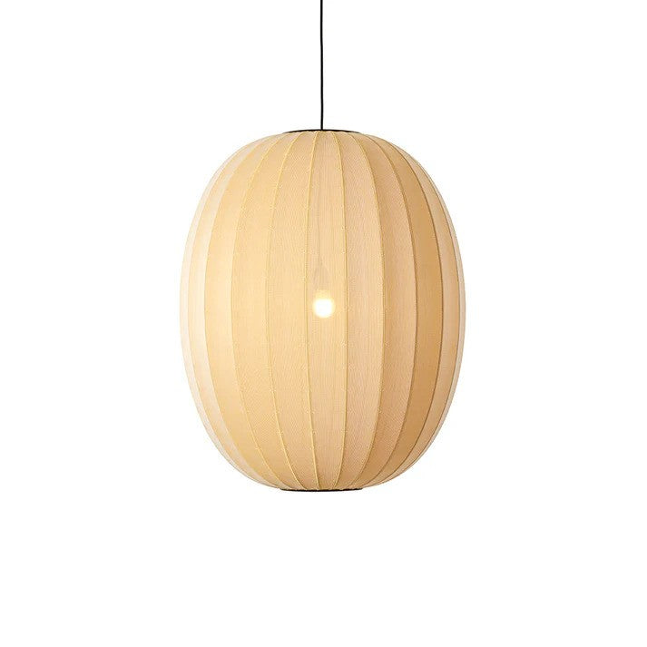 Den æstetiske Knit-Wit Ø65 High Oval Pendel i Sunrise hængt op foran en hvid væg med en E27 pære iført for den behagelige belysning