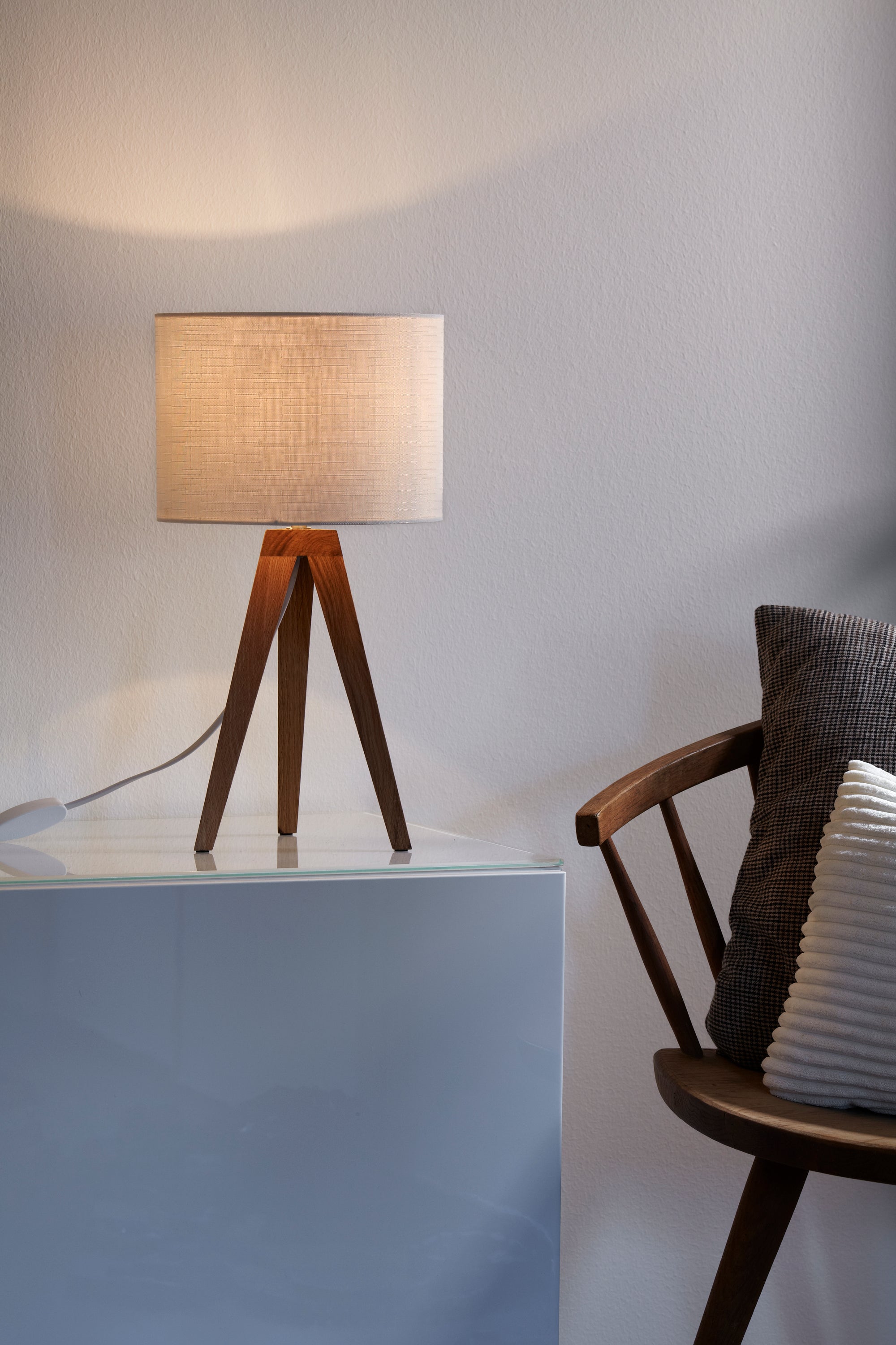Kullen Bordlampe 1L i Træ/Hvid placeret på hylden i stuen for hyggelig belysning