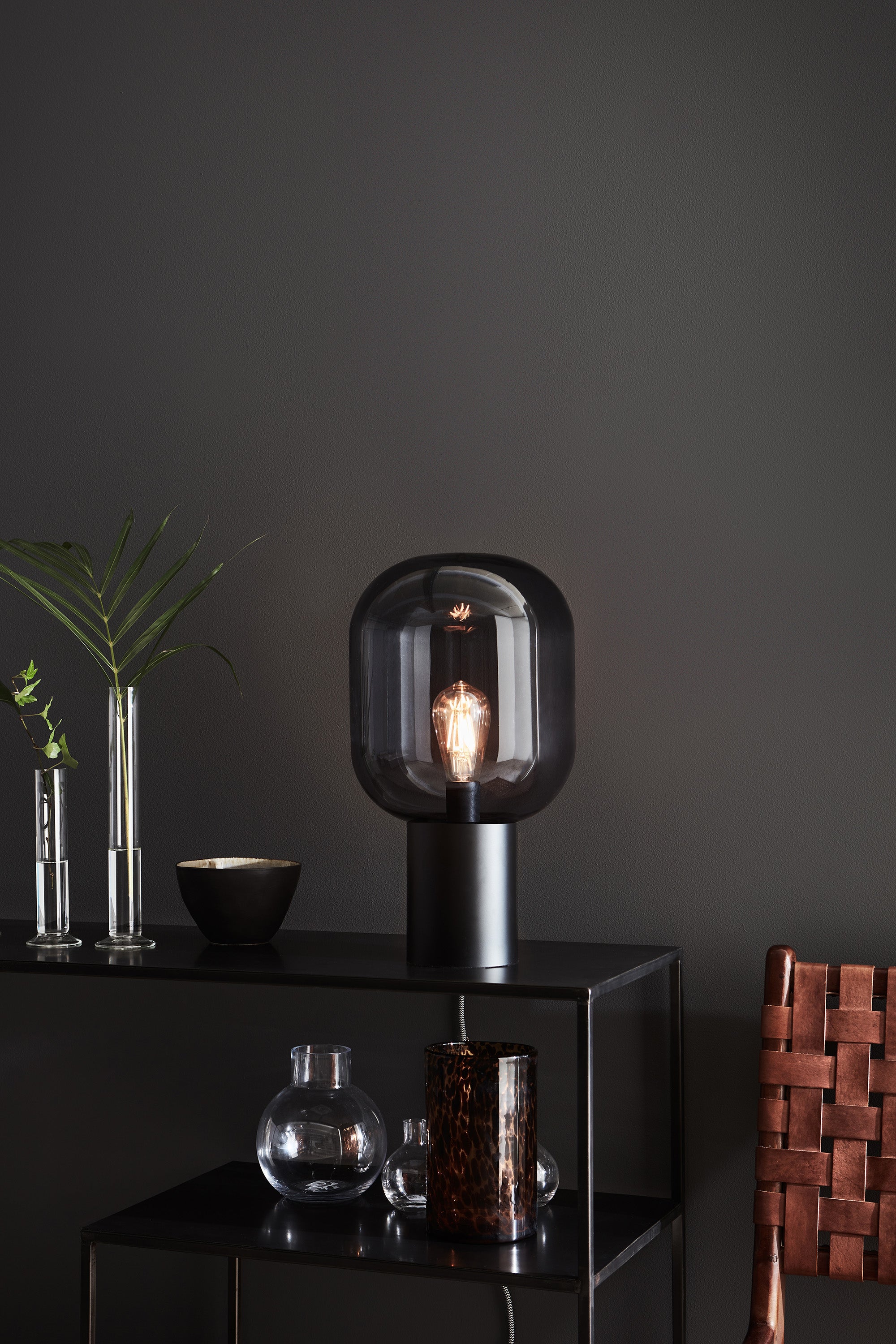 Markslöjd's unikke Bordlampe Brooklyn Bordlampe 1L 44cm i Sort/Røg placeret på en hylde i stuen