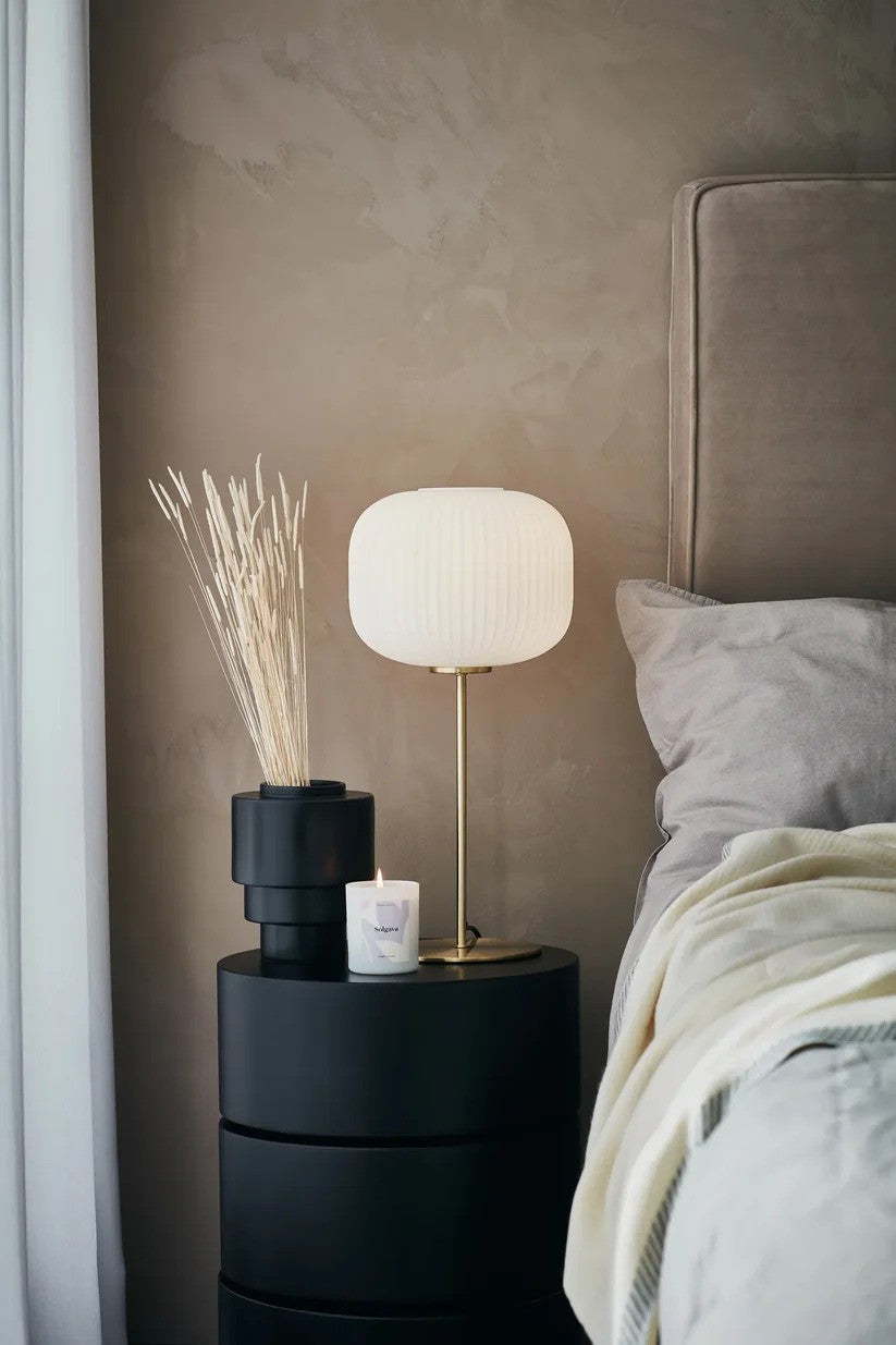 Markslöjd's Sober Bordlampe i Messing/Hvid 50 cm i højde placeret på sengekanten