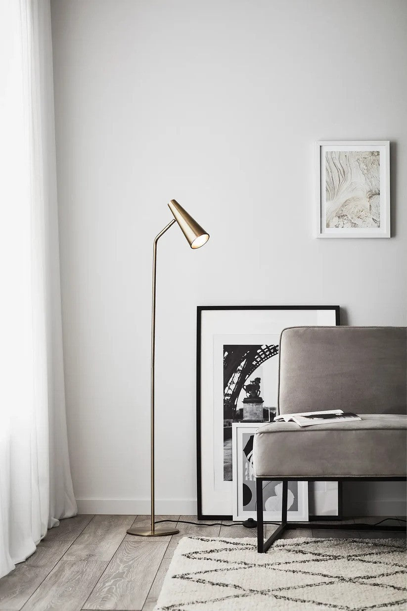 Markslöjd's stilrene Peak Gulvlampe i Antique farvet placeret i hjørnet af stuen for det behagelige lys og elegante look