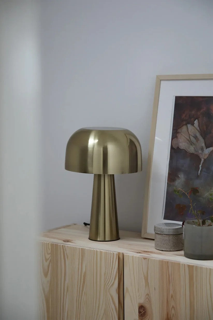 Den æstetiske lampe fra Markslöjd Blanca Bordlampe i Bronze stillet på hylden i stuen