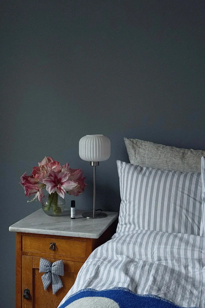 Sober Bordlampe i Stål/Hvid sat på sengebordet for det æstetiske design og behagelige lys