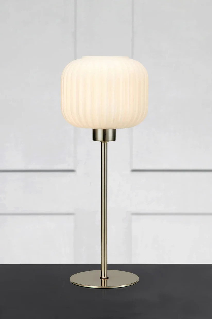 Sober Bordlampe i Stål/Hvid sat på et bord foran en væg for kontrasten