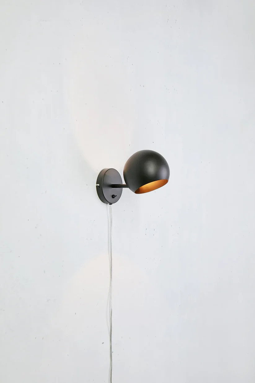Den æstetiske lampe Edgar Væglampe i Sort hængt op på en væg for kontrasten