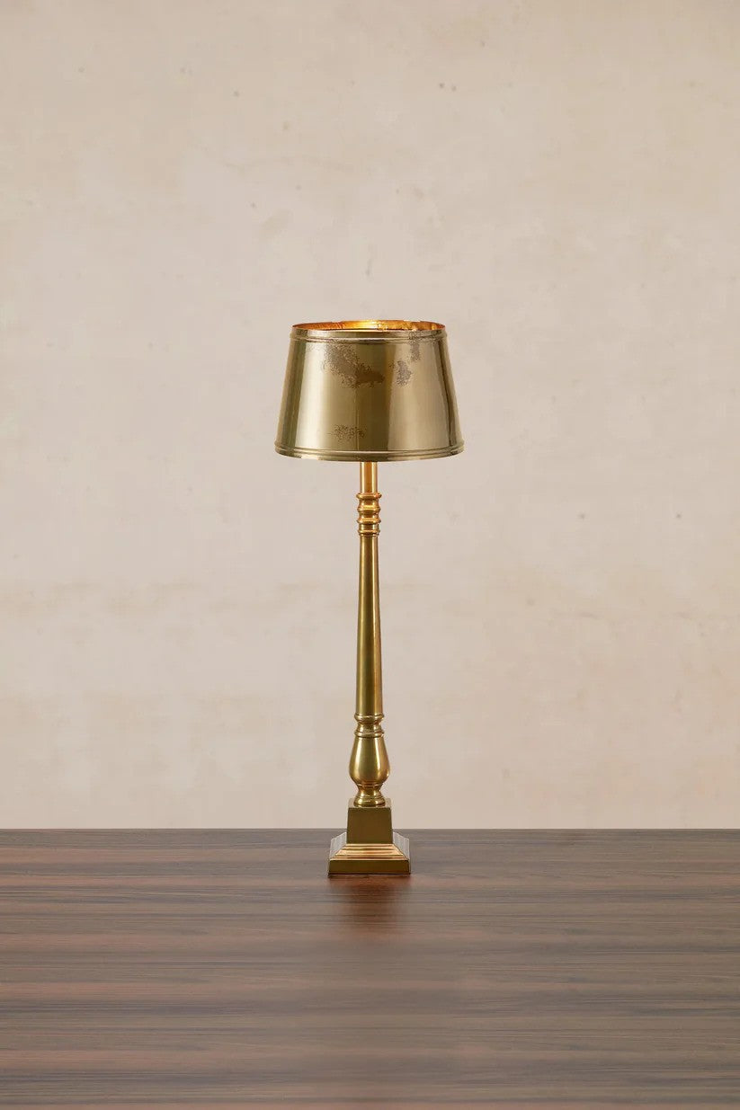 Den æstetiske Metallo Bordlampe i Messing sat foran en væg med flot kontrast