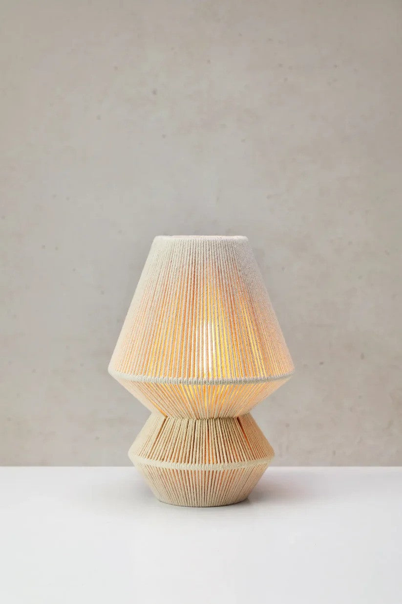 Razzo Bordlampe 34cm i Beige stillet på et bord foran en væg med en flot kontrast