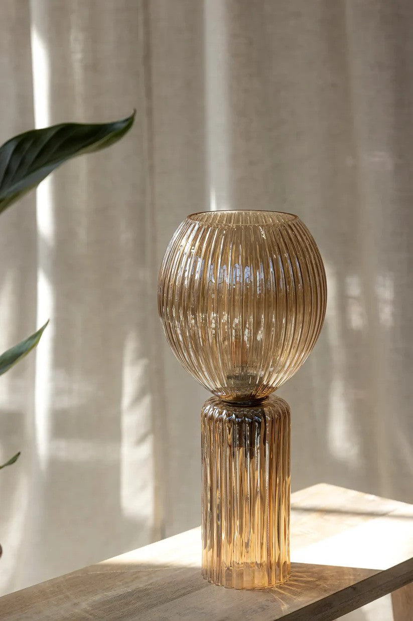 Den elegante og unikke Toulipa Bordlampe i Ravgul placeret i stuen på en skammel
