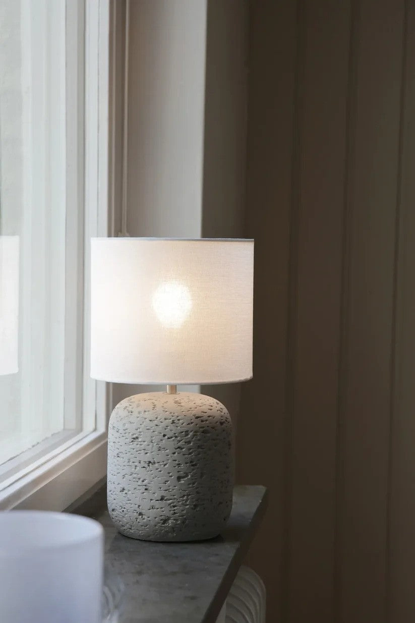 Den æstetiske og unikke designet Motagna Bordlampe 32cm i Grå sat op i vindueskammen