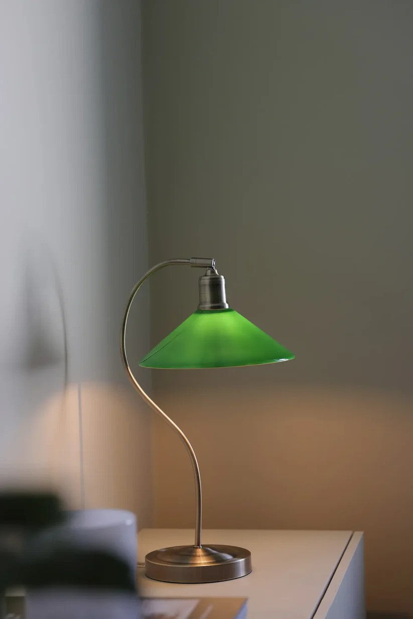 Den æstetiske Vela Bordlampe i Grøn placeret på en skuffe