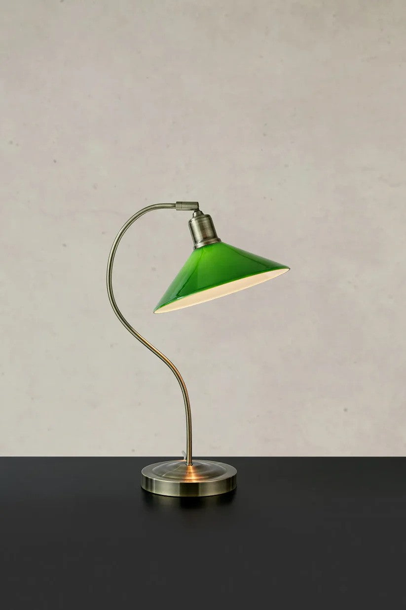 Den elegante og unikke designet Vela Bordlampe i Grøn placeret på et bord foran en væg med en flot kontrast