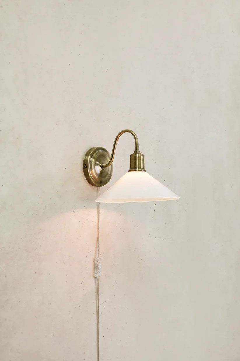 Den elegante designet Vela Væglampe i Hvid hængt op på en væg med en flot kontrast