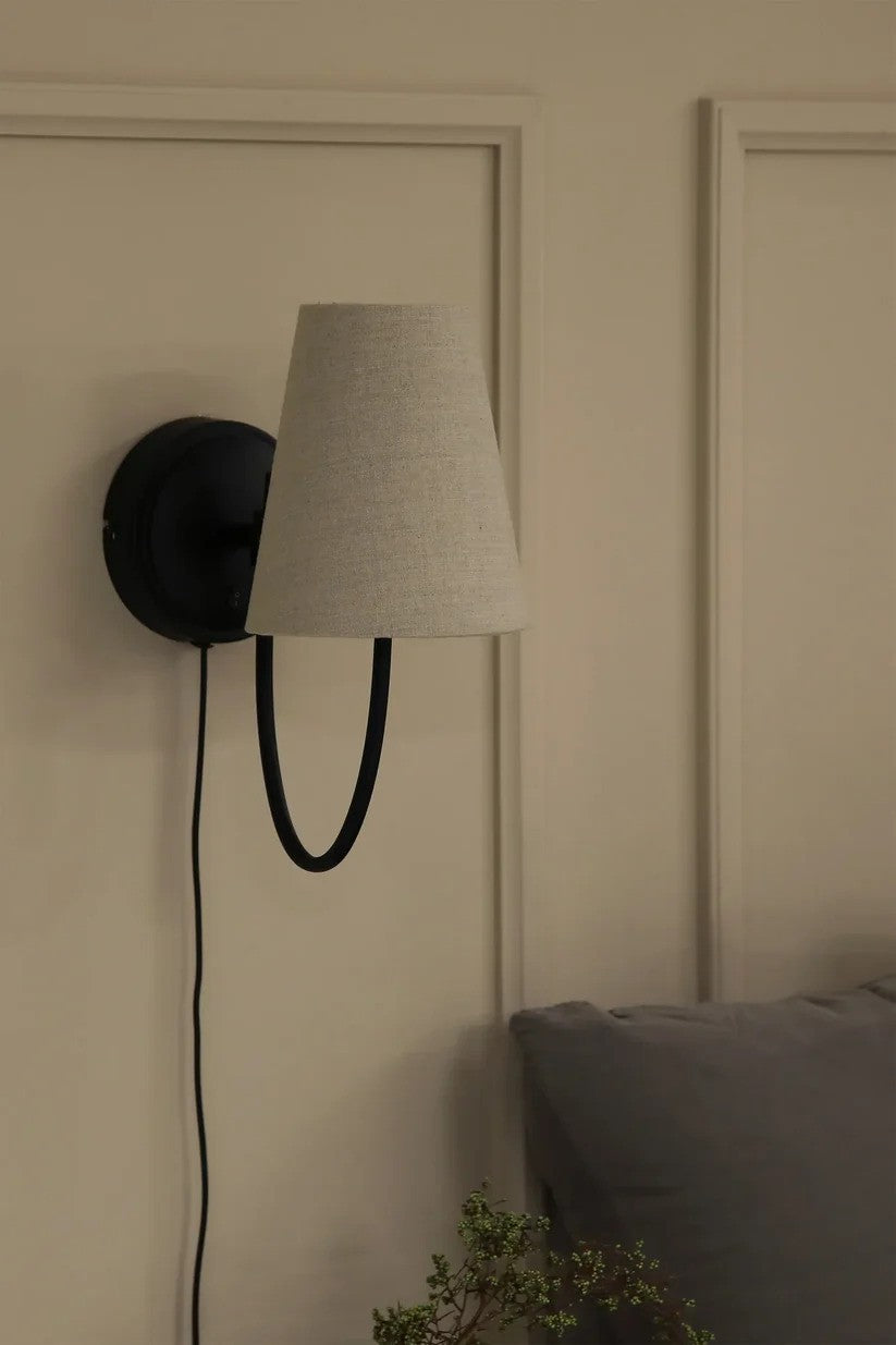 Den elegante Amar Væglampe i Beige/Sort hængt op i soveværelset