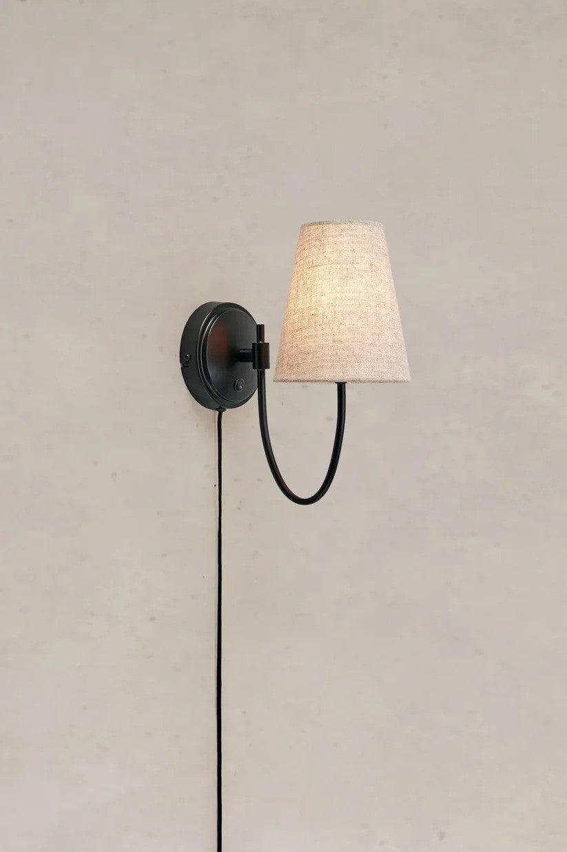 Den unikke designet Amar Væglampe i Beige/Sort hængt op på en væg med en flot kontrast