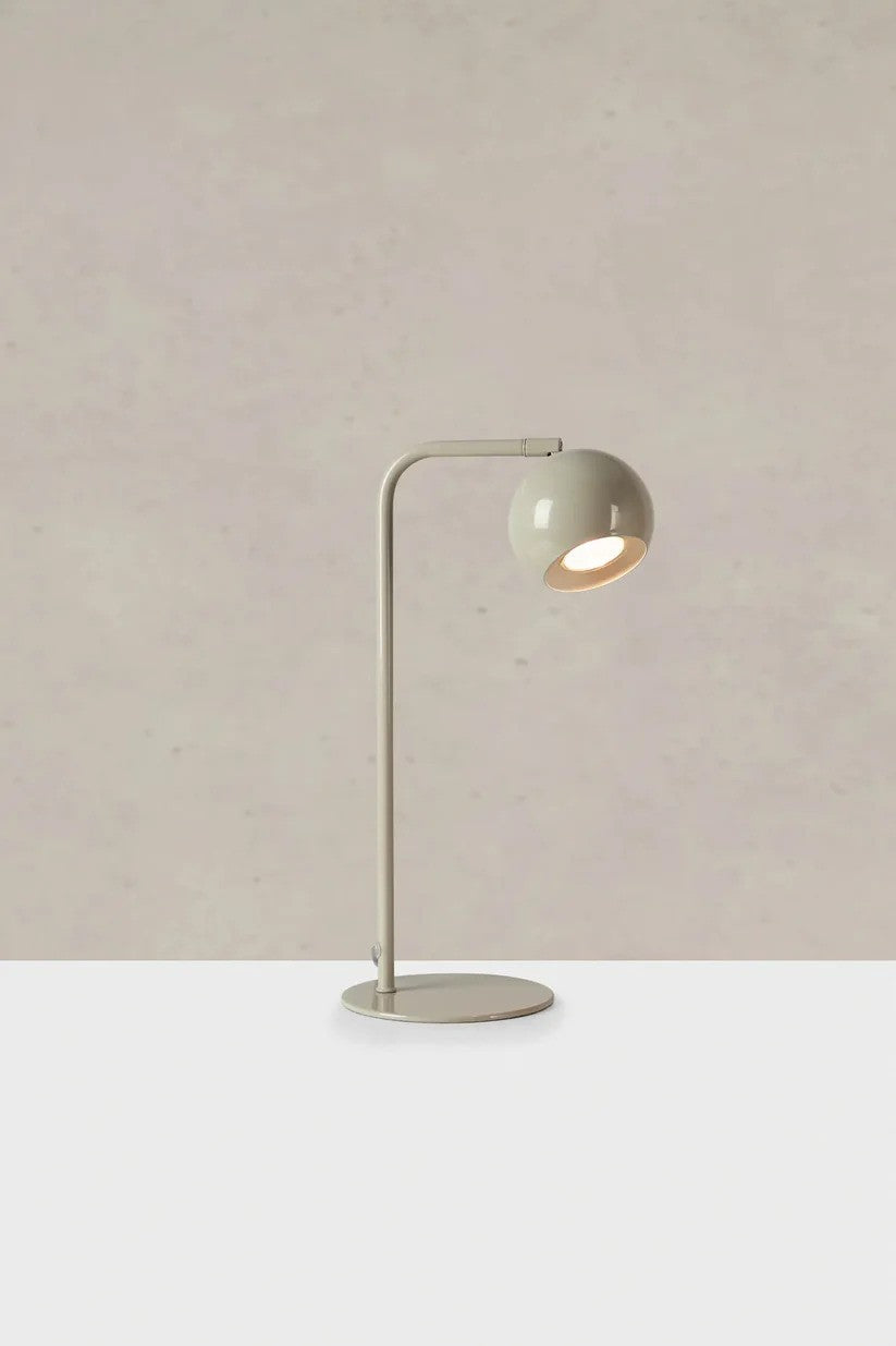Markslöjd's æstetiske Pop Bordlampe i Grå stillet på et bord foran en væg med en flot kontrast