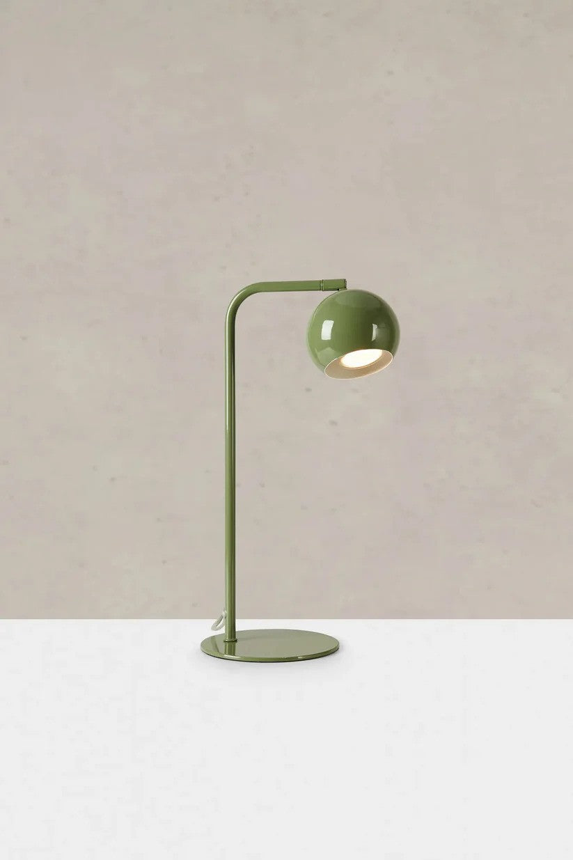 Den unikke designet Pop Bordlampe i Grøn stillet på et bord foran en væg med en flot kontrast