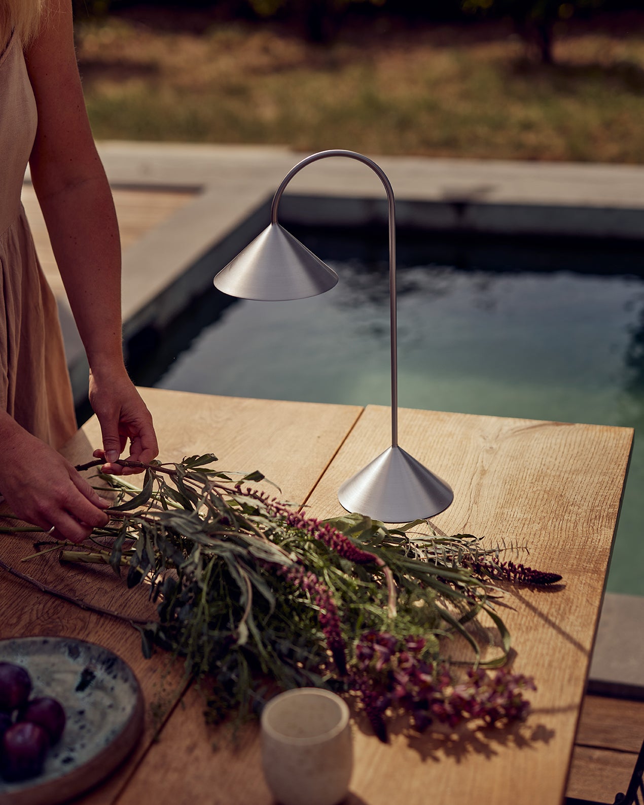 Den unikke og skandinaviske designet Grasp Portable H47 i Brushed Stainless Steel placeret udenfor på bordet for dens behagelige belysning
