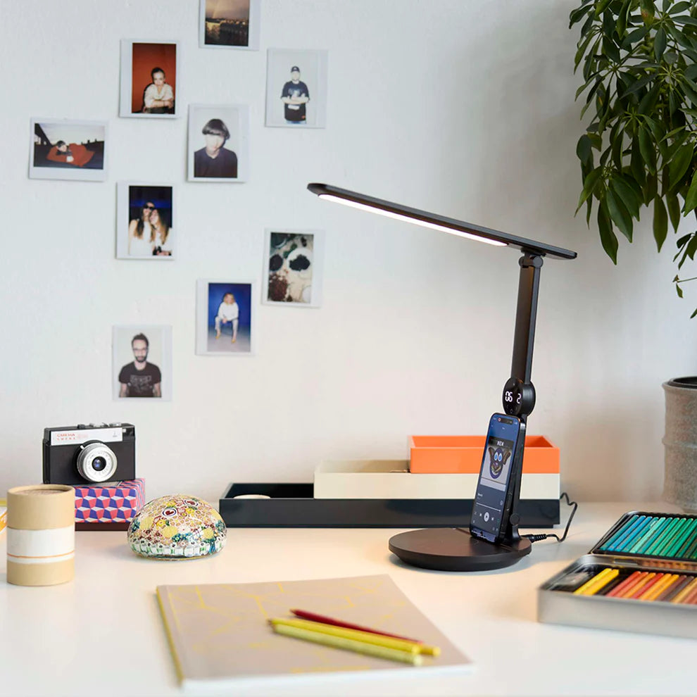 Den æstetiske Opus LED Bordlampe i Sort placeret på arbejdsbordet for dens varme belysning