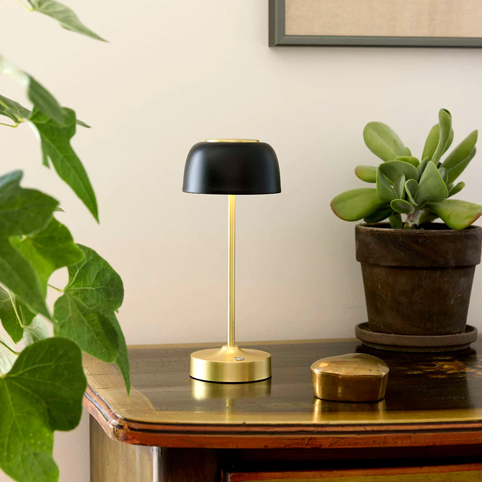 Den unikke designet Royal LED Bordlampe i Sort/Guld placeret på en hylde i stuen for dens behagelige belysning