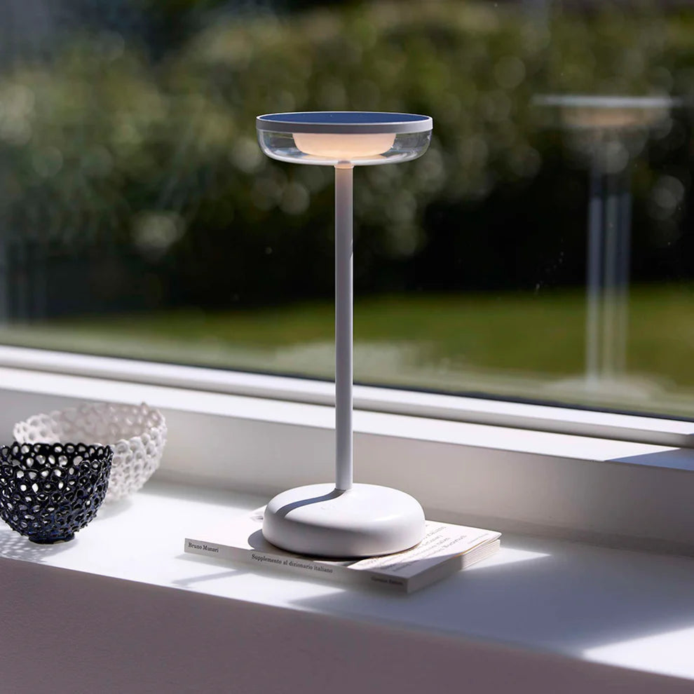 Den æstetiske Breeze LED Bordlampe i Hvid placeret i vindueskammen for dens behagelige belysning og opladning på solcelle