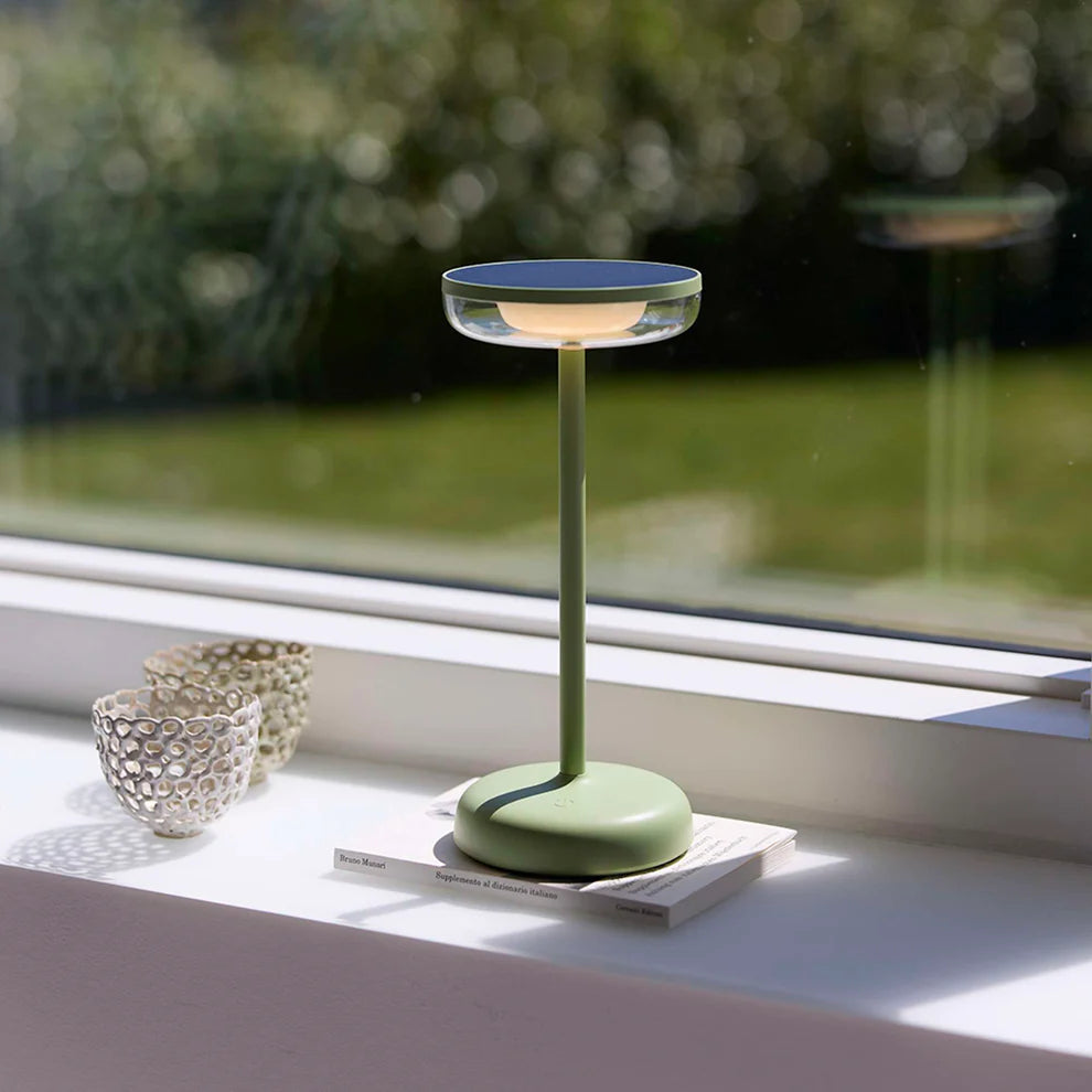 Den æstetiske Breeze LED Bordlampe i Støvet Grøn placeret i vindueskammen for dens behagelige belysning