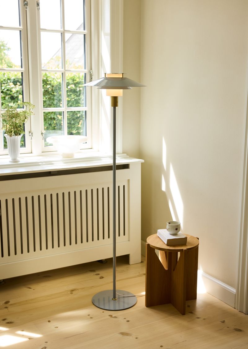 Rivoli Gulvlampe Grå placeret i hjørnet af stuen for dens unikke design og varme belysning