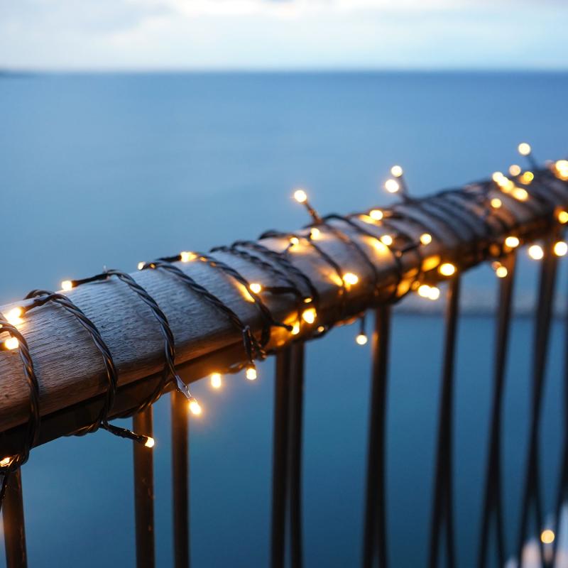Den æstetiske Top-Line Energy Supplementsæt 100 LED 10m i Sort placeret på gelænderet udenfor for dens hyggelige stemningsfulde belysning