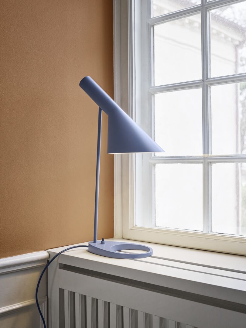 arne jacobsen bordlampe i smuk ny blå nuance i en vindueskarm