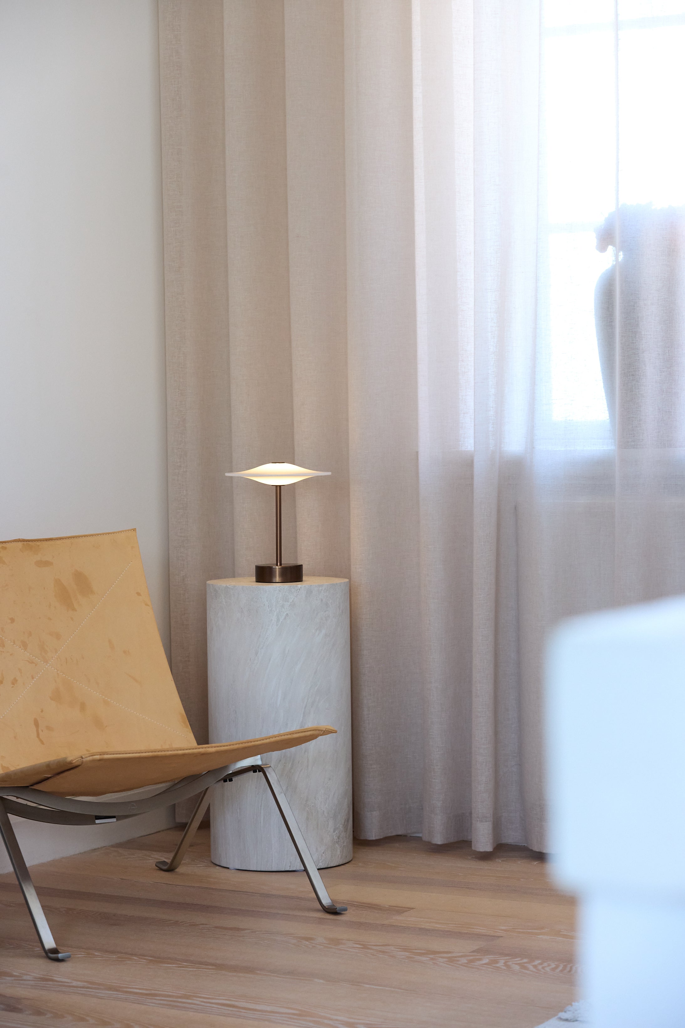 Den unikke skandinaviske designet Piet Hein Sinus22 Bordlampe i Aged Bronze placeret i hjørnet af stuen for dens behagelige belysning