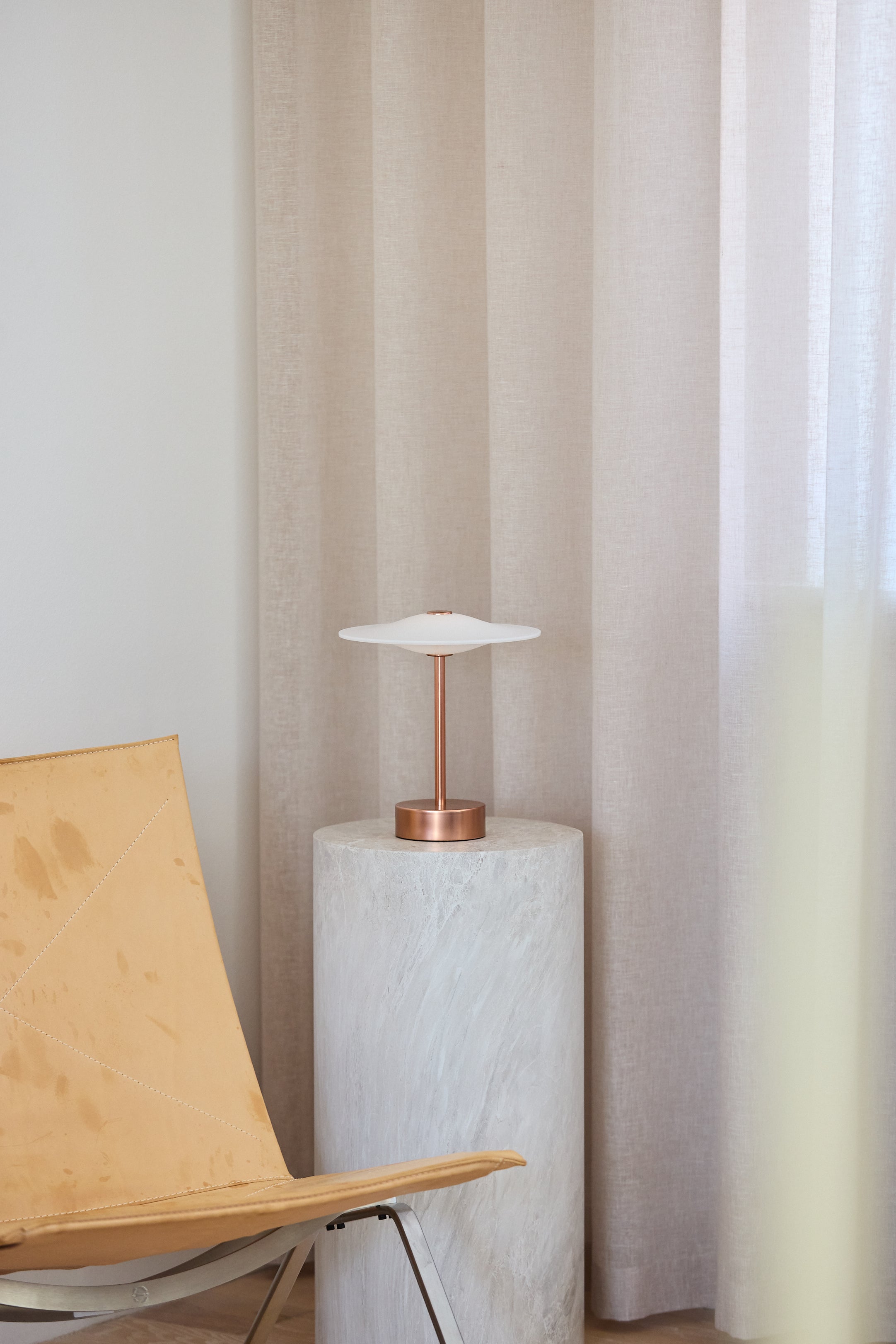 Den unikke designet Piet Hein Sinus22 Bordlampe i Kobber placeret i hjørnet af stuen for dens behagelige belysning