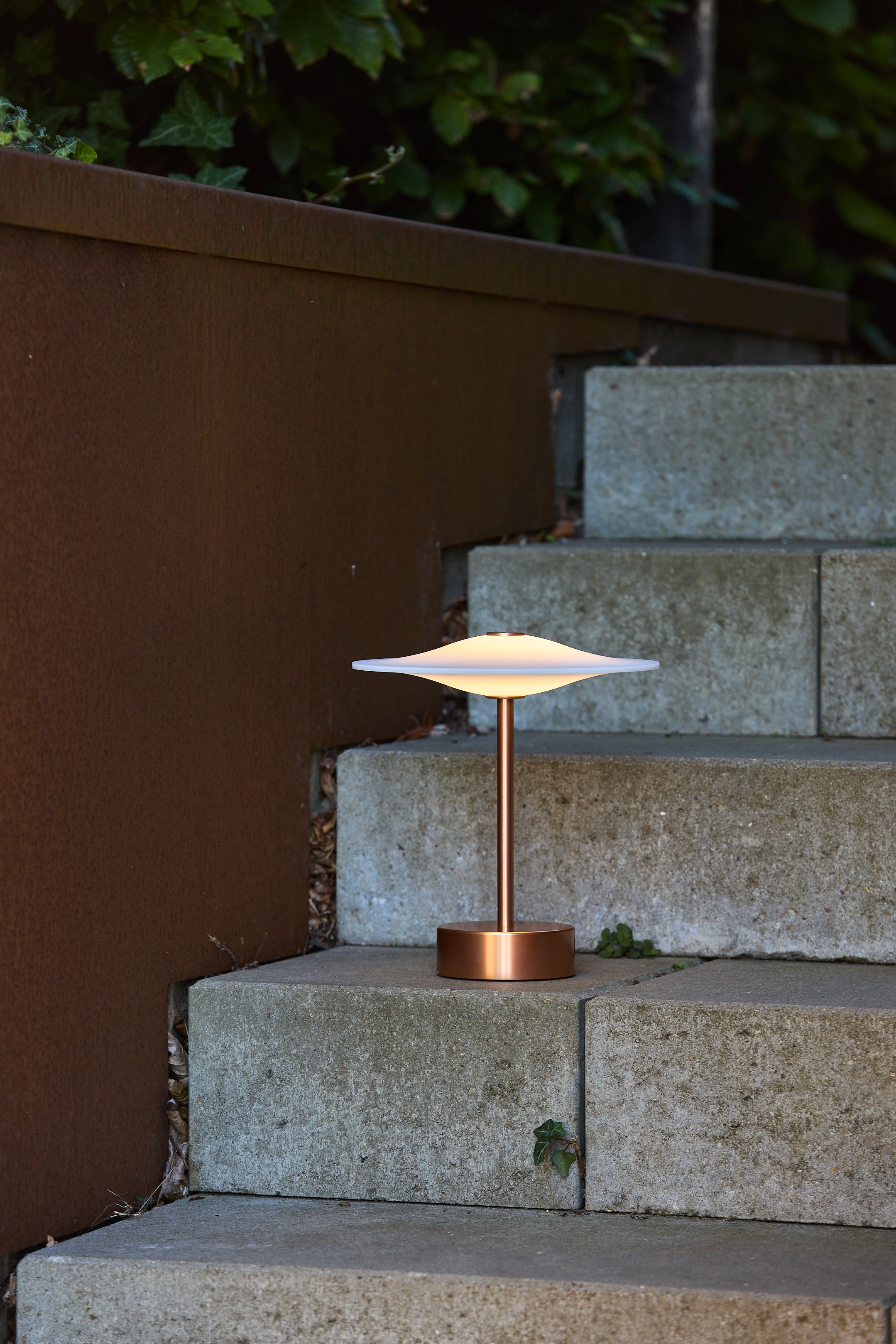 Piet Hein Sinus22 Bordlampe i Kobber placeret udenfor på trapperne for dens flotte belysning