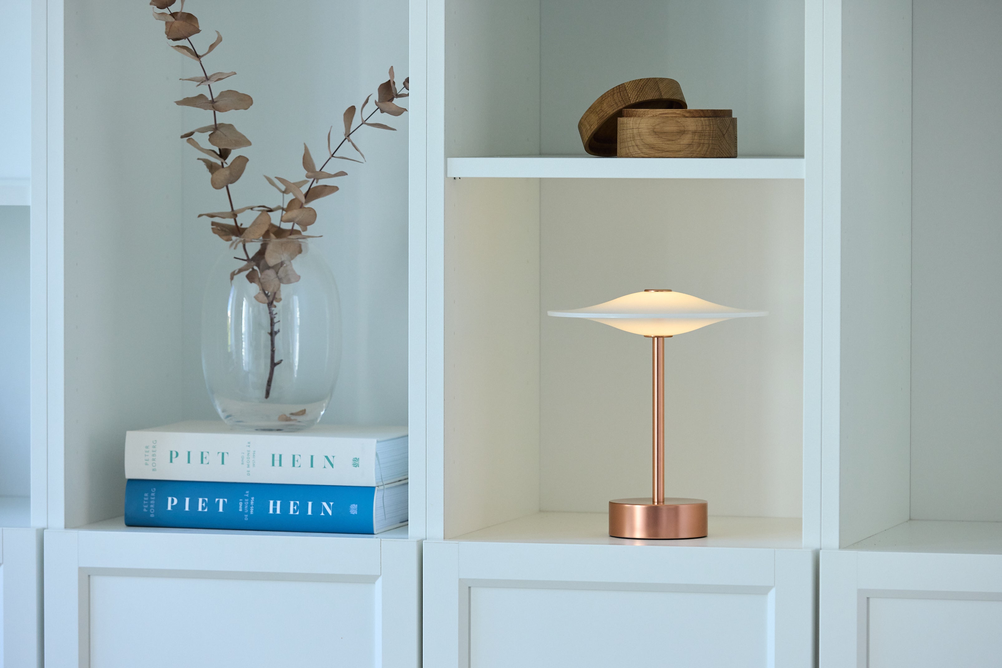 Piet Hein Sinus22 Bordlampe i Kobber placeret på hylden i stuen for dens elegante design