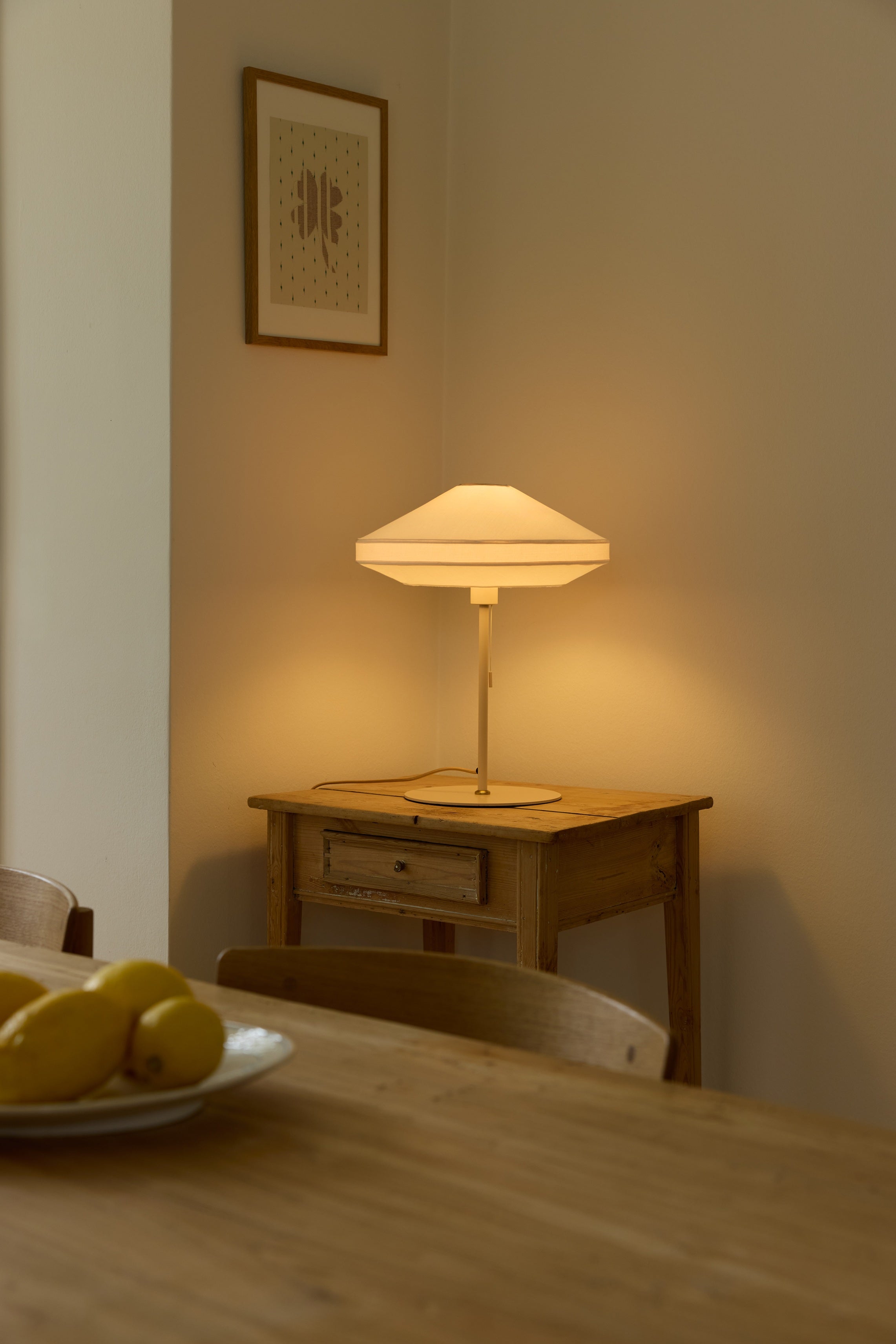 Den unikke designet Paris Soft Bordlampe Ø40 placeret på et bord i hjørnet af stuen for dens varme belysning