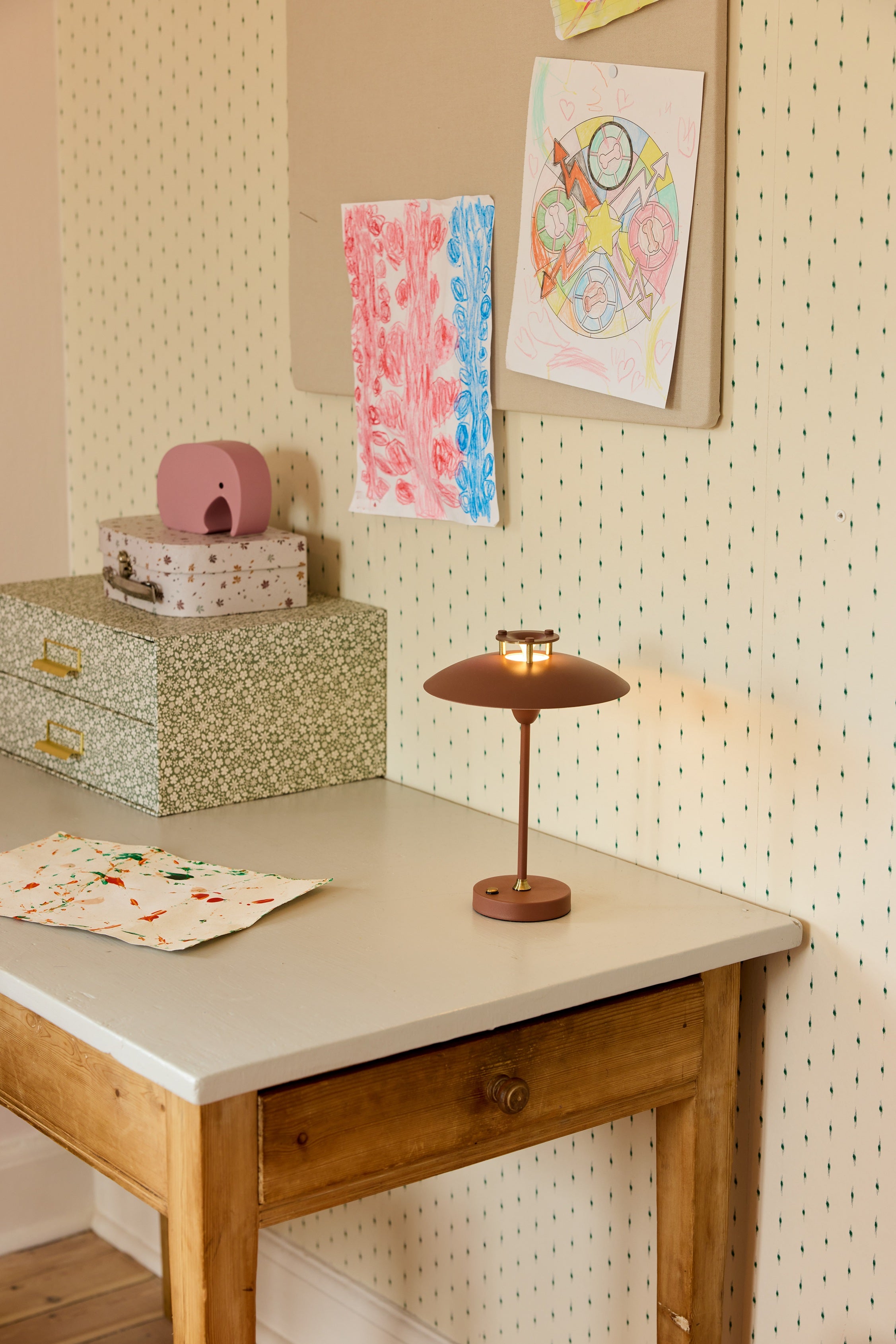 Den unikke designet Mini Stepp 1-2-3 Portable Bordlampe i Terracotta placeret på læsebordet for dens behagelige belysning