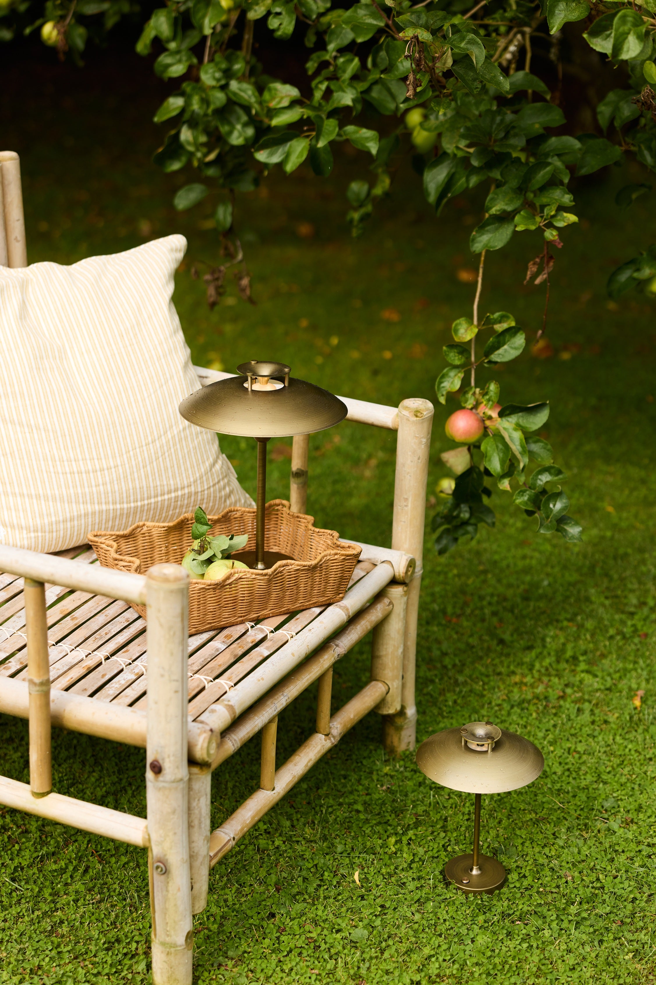 Den unikke og skandinaviske designet Mini Stepp 1-2-3 Portable Bordlampe i Antique placeret udenfor på en stol for dens hyggelige belysning