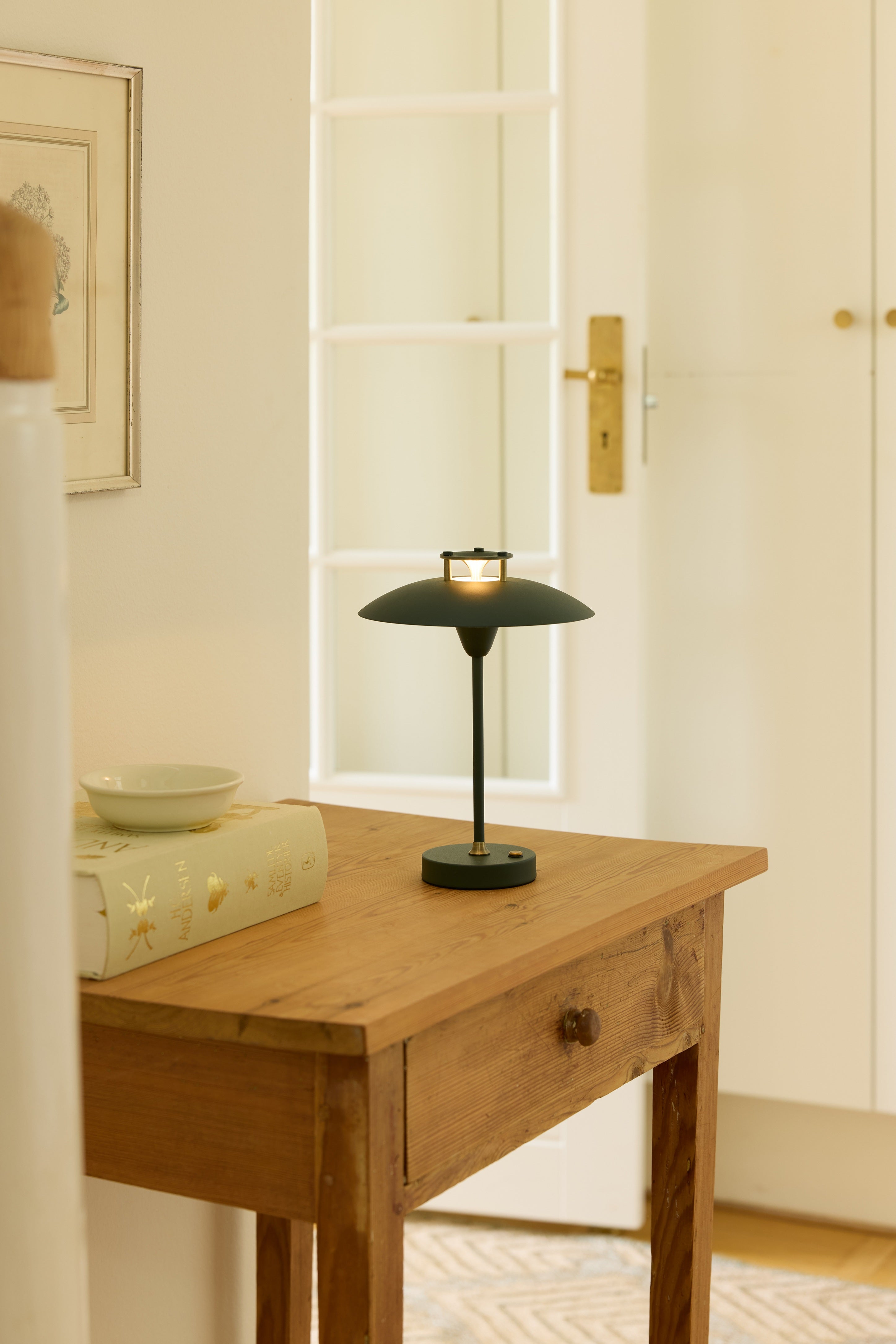 Zoomet ind på den unikke designet Mini Stepp 1-2-3 Portable Bordlampe i Mørk Grøn placeret på en skuffe i stuen