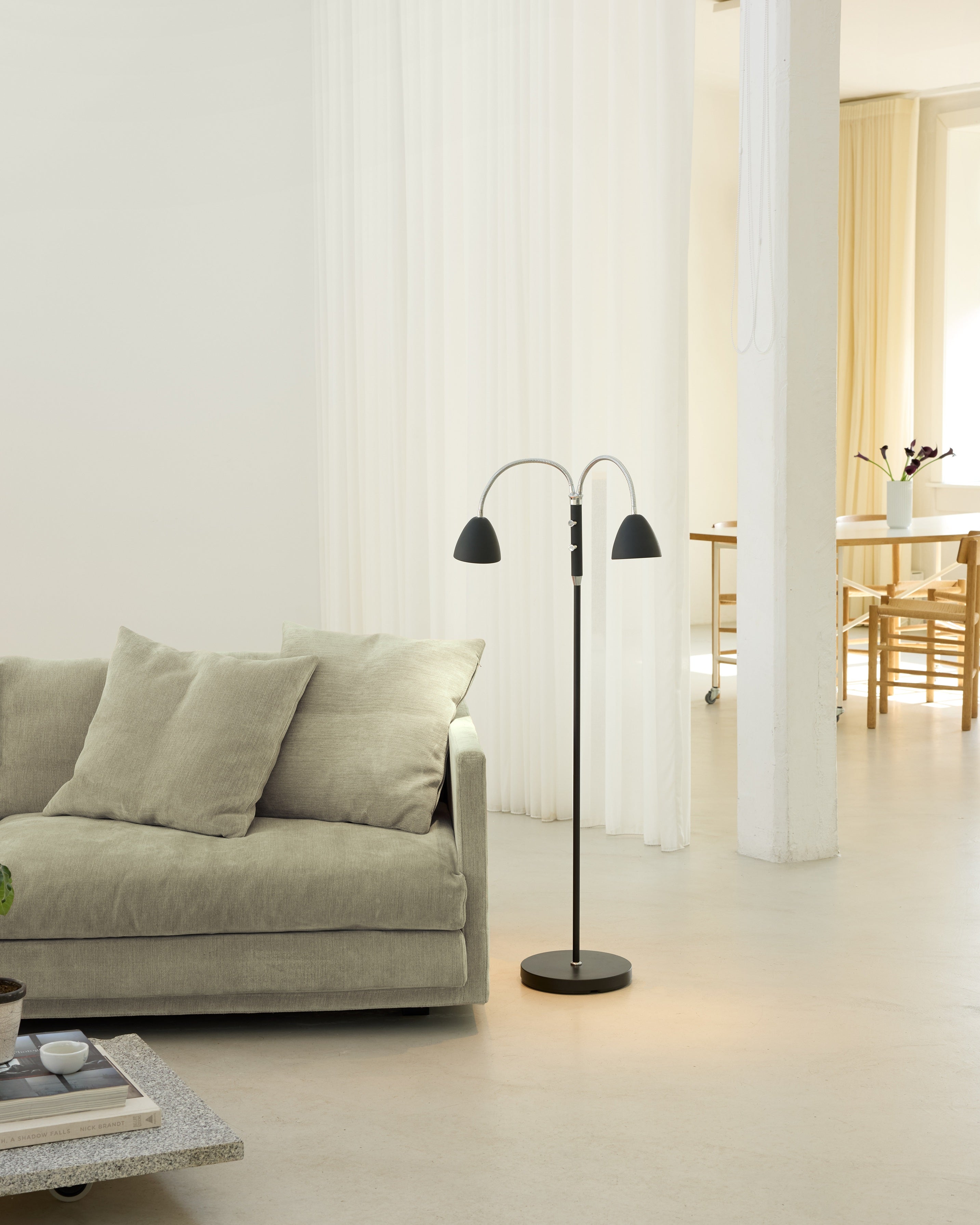 Den æstetiske Room 2-Arm Gulvlampe i Sort Krom placeret i stuen for dens behagelige belysning