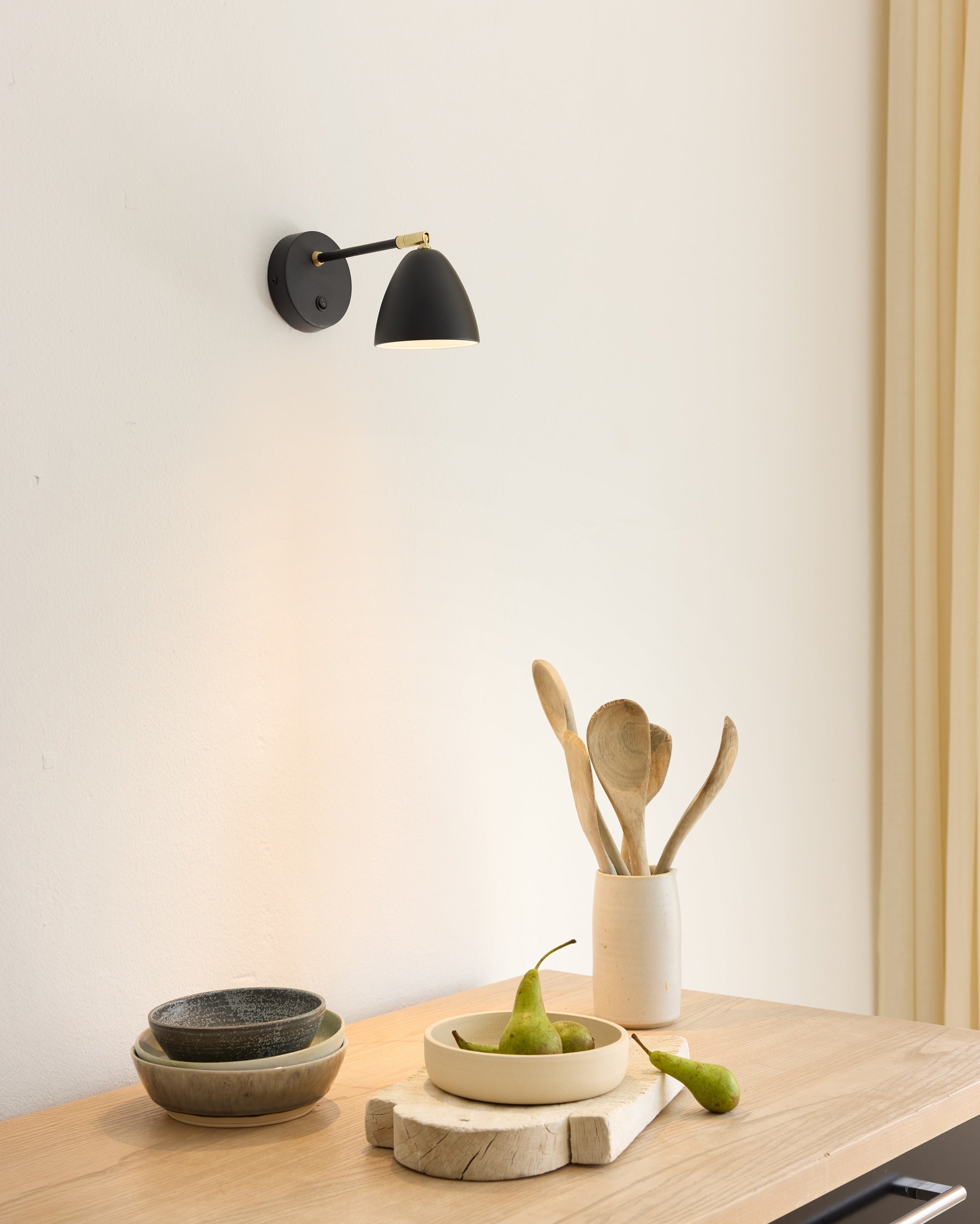 Den unikke og elegante designet Room Væglampe i Sort/Messing hængt op i stuen for dens behagelige belysning